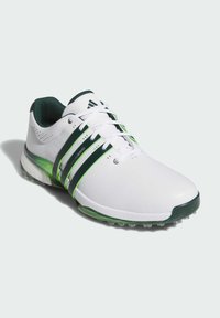 Zapatilla deportiva blanca con acentos verdes. Presenta un diseño elegante, parte superior texturizada y múltiples franjas verde oscuro. Los detalles incluyen una suela de goma.