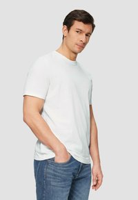 Weißes Baumwoll-T-Shirt mit Rundhalsausschnitt und kurzen Ärmeln, kombiniert mit blauen Jeans. Schlichtes Design, leichtes Material und lässige Passform.