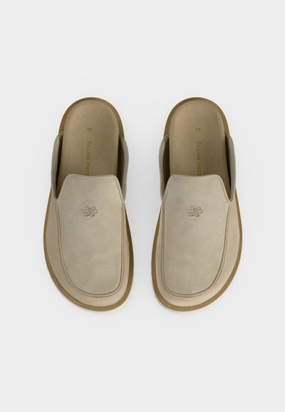 Ζευγάρι μπεζ παντόφλες από σουέντ δέρμα με στρογγυλεμένες τετράγωνες μύτες και καουτσούκ σόλες, φωτογραφημένες από πάνω σε λευκό φόντο.