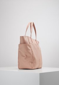 Vaaleanpunainen nahkainen olkalaukku, jossa on kaksi pitkää kahvaa, suorakulmainen muoto, teksturoitu pinta ja kaksi sivutaskua. Kultaiset koristeosat reunoilla.