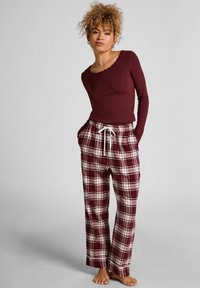 Bordeaux langemouwen top met een scalloped halslijn, gecombineerd met loose-fit geruite pyjamabroek in rood, wit en bordeaux, met een elastische tailleband.