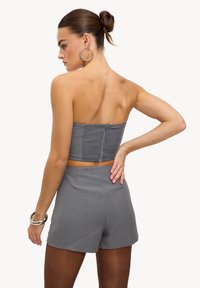 Ensemble gris deux pièces comprenant un haut bustier à texture froncée avec fermeture éclair, associé à un short assorti et ajusté.