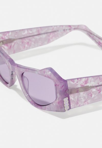 Gafas de sol moradas con patrón veteado, de montura angular y lentes tintados; cuentan con un detalle metálico en el lateral con la marca en texto blanco.