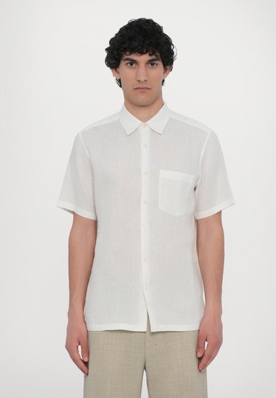 Chemise blanche à manches courtes en tissu léger, avec un col classique, des boutons sur le devant et une poche côté cœur. Texture lisse.