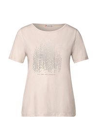 Camiseta de color beige claro hecha de algodón suave, con un gráfico del horizonte de la ciudad en plata y el texto "MANTENTE CÓMODO, MANTENTE CONECTADO" debajo. Manga corta.