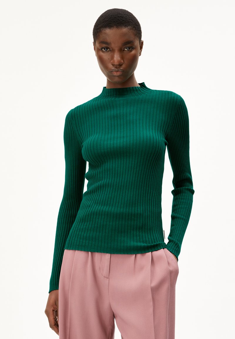 Groen geribbeld shirt met lange mouwen en een hoge nek, gecombineerd met lichtroze plissébroek. De stof vertoont een gestructureerd, slim fit ontwerp.