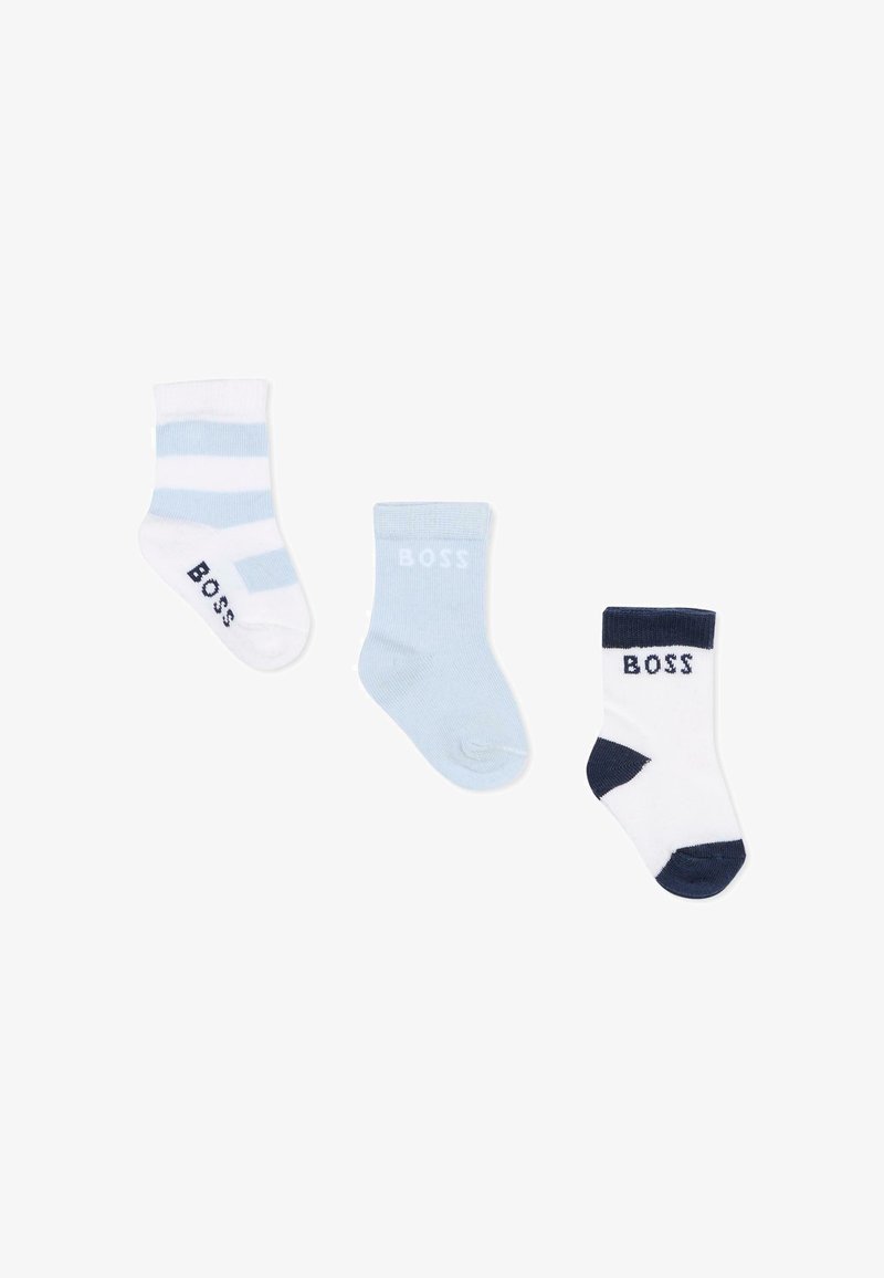 Trois chaussettes pour bébé : rayures blanches et bleu clair, bleu clair uni, et blanche avec talon et bout marine, toutes avec le logo "BOSS".