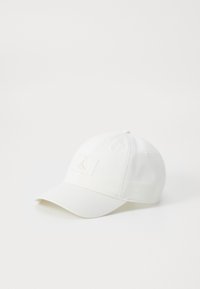 Hvid baseballkasket lavet af bomuld med en flad skygge, der har et diskret logo-patch i lys tan på forsiden og en knap på toppen.