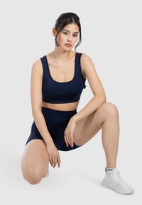Set sportivo blu navy composto da un top corto con spalline larghe e pantaloni corti a vita alta, realizzati in un tessuto liscio e elasticizzato.