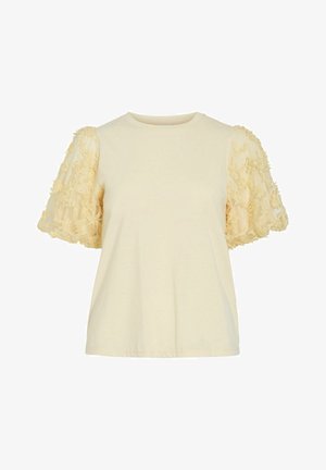 Lühike kreemjas pluus ümarate kaelusega ja läbipaistvate puhvis varrukatega, mida kaunistavad tekstuuriga lilleaplikatsioonid.