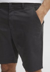 Sorte shorts lavet af glat stof, med sidelommer, knaplukning og lige skæring i kanten.