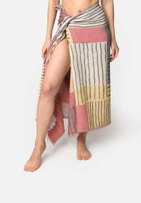 Colorful woven wrap skirt with geometric patterns in pink, yellow, and gray, featuring fringed edges and a knot at the waist.