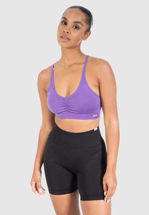 Paarse geribde crop top met geplooide details en dunne banden, gecombineerd met hoge zwarte shorts gemaakt van rekbaar materiaal.