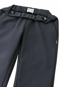Dunkelgraue Hose aus glattem Stoff mit einem gerafften Bund, zwei Knöpfen und einem kleinen Markenetikett an der Seite.
