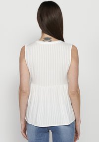 Blusa bianca senza maniche con righe verticali, vita a peplo e scollatura arrotondata, realizzata in tessuto leggero; texture liscia.