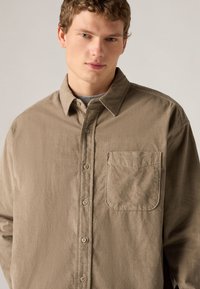 Χακί πουκάμισο με κουμπιά κατασκευασμένο από απαλό ύφασμα, με τσέπη στο στήθος, απαλό γιακά και άνετη εφαρμογή με λεπτή υφή.