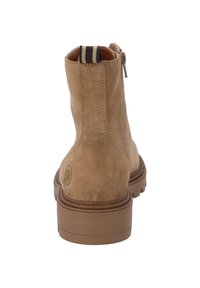 Bottine en daim beige avec coutures renforcées, bout rond et semelle en caoutchouc. Comprend une languette rayée beige à l'arrière.