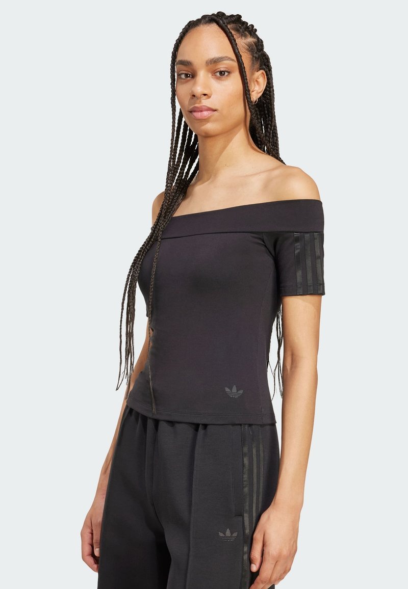 Musta olkaimeton paita lyhyillä hihoilla, jossa on teksturoituja pystysuoria raitoja hihoissa ja pieni logo helmassa.