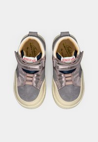 Szare sneakersy do kostki z błyszczącym metalicznym wykończeniem, paskami na rzepy i teksturowaną podeszwą. Wnętrze ma jasne wykończenie i branding.