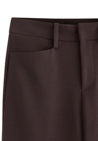 I pantaloni marroni su misura presentano una vita strutturata, tasche a filetto e una stoffa testurizzata con una finitura liscia.