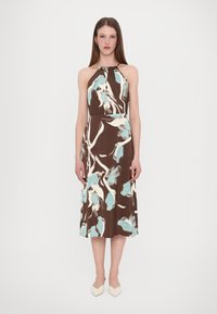 Robe halter marron avec des motifs floraux bleu clair et blanc. Le tissu a une texture lisse, et le design s'étend jusqu'à mi-mollet.