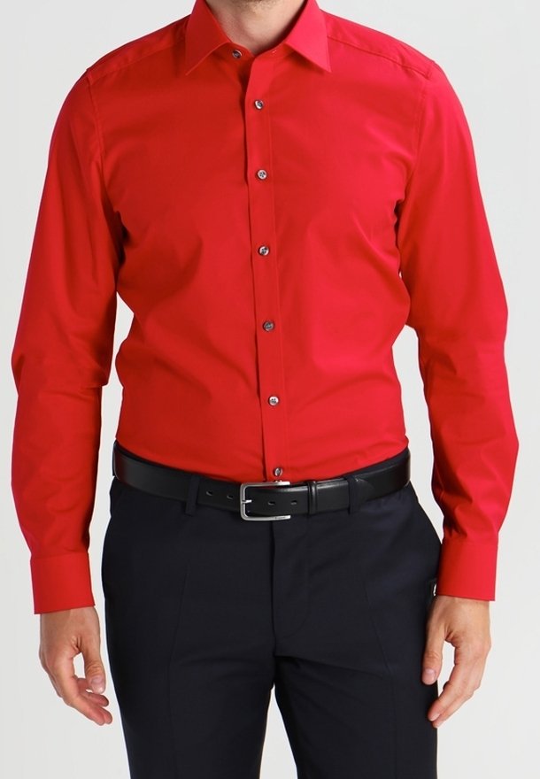Rotes Langarmhemd aus Baumwolle mit glatter Textur; verfügt über eine durchgehende Knopfleiste und einen spitzen Kragen, getragen mit dunkler Hose und schwarzem Gürtel.