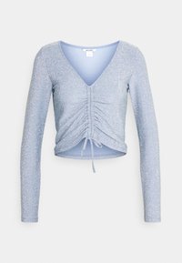 Lichtblauw, langärmelig top gemaakt van glitterstof; heeft een diepe V-hals en plooien met een strikdetail aan de onderkant. Cropped ontwerp.