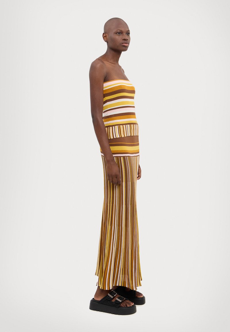 Rochie maxi fără bretele, cu dungi verticale multicolore în nuanțe pământii, având un corset ajustat și o fustă plisată, fluidă. Sandale cu platformă negre.