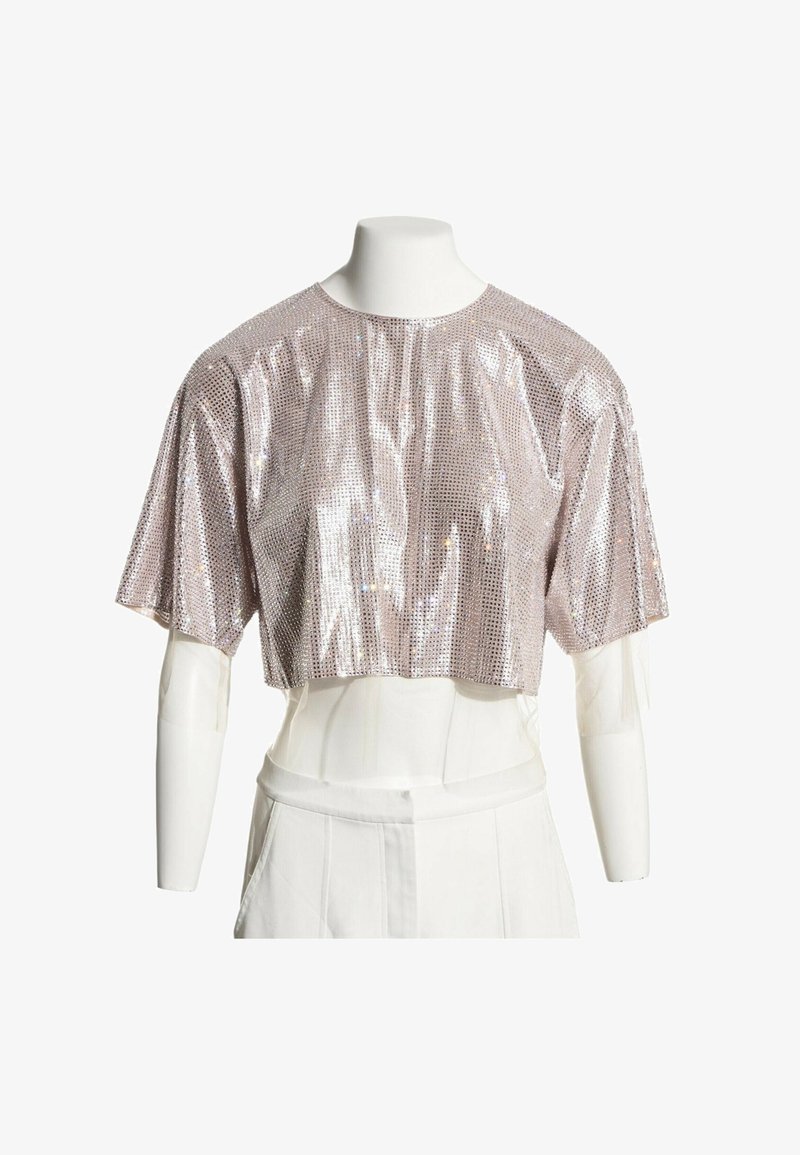 Haut court à manches courtes avec sequins argentés sur un buste de mannequin blanc sur fond blanc.