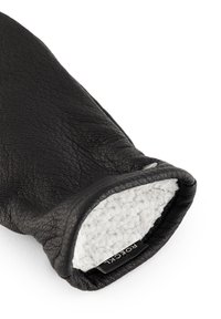 Schwarzer Lederhandschuh mit strukturierter Außenseite und weichem, weißem, flauschigem Innenfutter. Verfügt über ein Etikett an der Öffnung.