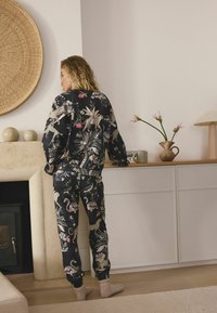 Czarny komplet piżamowy z kolorowymi wzorami zwierząt i kwiatów, o luźnym kroju i elastycznych mankietach. Miękka faktura i casualowy design.