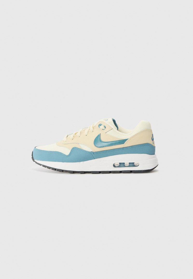 Helle blaue und cremefarbene Sportschuhe mit strukturiertem Obermaterial, ausgestattet mit einer sichtbaren Luftpolsterung, runder Spitze und kontrastierender dunkler Sohle.