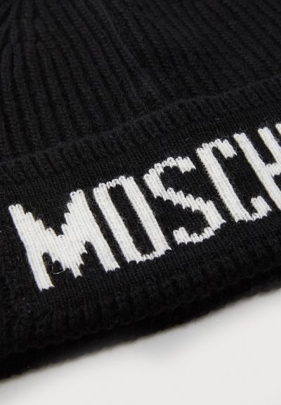 Svart stickad mössa med ribbat mönster och breda uppvik, prydd med varumärket "MOSCHINO" i stora vita bokstäver längs kanten.