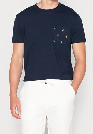 T-shirt in cotone blu navy con maniche corte e tasca sul petto, decorata con forme colorate ricamate in verde, giallo e rosso.