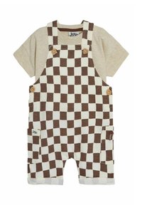 Pantalones cortos de tirantes a cuadros en marrón y crema con una camisa de manga corta beige, que cuenta con botones de madera y bolsillos laterales. Textura de tela suave.