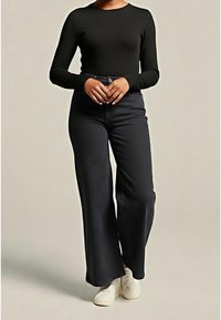 Haut noir à manches longues associé à un pantalon noir taille haute à jambes larges. Le tissu semble lisse avec peu de détails. Des chaussures blanches complètent la tenue.