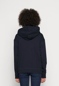 Felpa blu navy con cappuccio ampio, polsini e orlo a coste. Realizzata in un tessuto morbido, presenta una vestibilità comoda e ampia.
