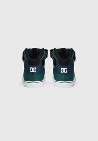 Hoge skate schoenen met een groen en zwart synthetisch oppervlak, een gevoerde kraag, een witte zool en een opvallend logo op de hiel.