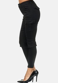 Black cargo pants with a fitted design, featuring side pockets and rolled cuffs, made of a smooth fabric with a slight stretch.