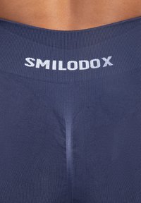 Leggings deportivos de color azul marino con una cinturilla acanalada que presenta "SMILODOX" en letras blancas. Textura suave, diseño ajustado, sin patrones visibles.