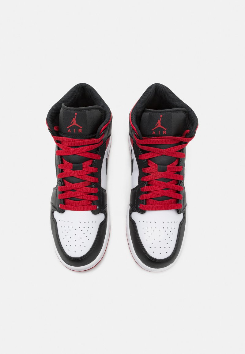 Wysokie sneakersy z czarną skórzaną cholewką, białym noskiem z perforacjami, czerwonymi sznurówkami oraz logo "Air Jordan" na języku.