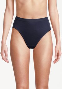 Donna che indossa una biancheria intima senza cuciture a vita alta di colore blu navy, in piedi con le braccia rilassate lungo i fianchi su uno sfondo bianco.