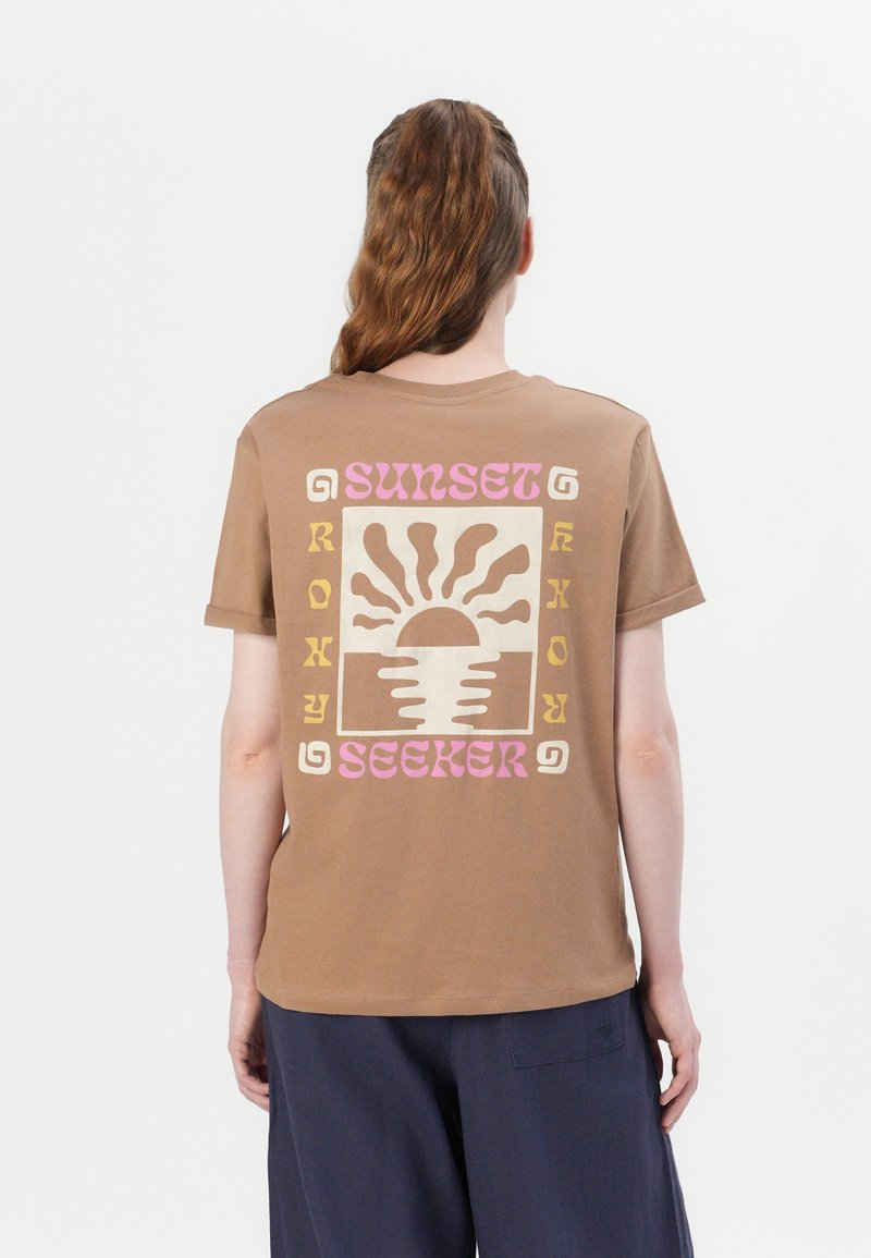Brown cotton t-shirt featuring a graphic design on the back with a sun and waves, highlighted in pink, orange, and cream colors.