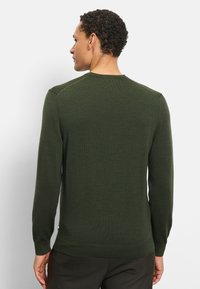 Maglione pullover verde in maglia con scollo rotondo, polsini e orlo a costine. Presenta una texture liscia e una silhouette aderente.