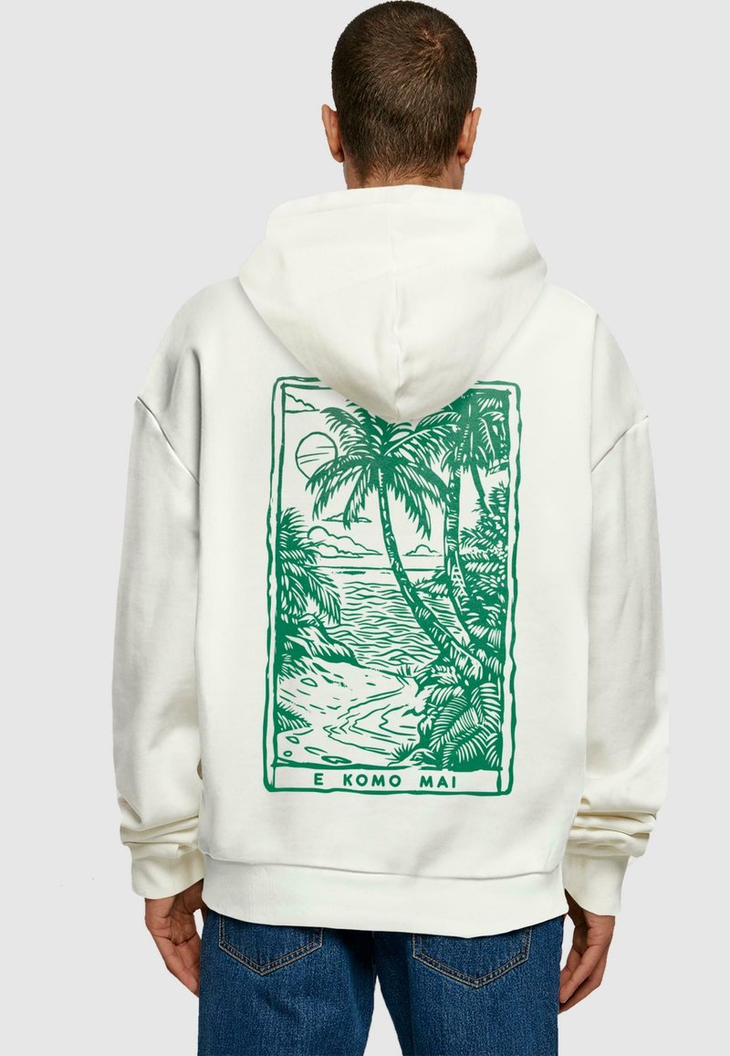 Weißer Hoodie mit einem grafischen Motiv einer grünen Landschaft auf der Rückseite, das Palmen und eine Strandszene innerhalb eines rechteckigen Rahmens zeigt.