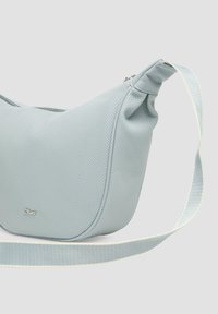 Hellblaues synthetisches Handtasche mit einer weichen, durchlöcherten Textur; geschwungene Form, Reißverschlussverschluss und ein flacher, verstellbarer Tragegurt mit einem hellen Akzent.