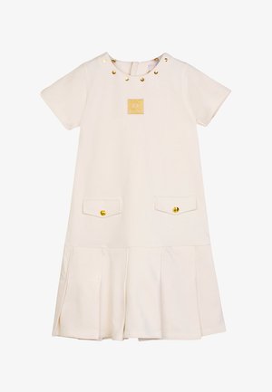 Abito color crema con maniche corte, borchie dorate attorno al collo, patch con logo centrato e due tasche anteriori con bottoni dorati.