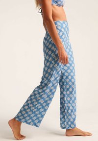 Pantalones de pierna ancha de patrón azul con un diseño floral en blanco y rosa. Hechos de una tela ligera con una textura fluida y un ajuste relajado.