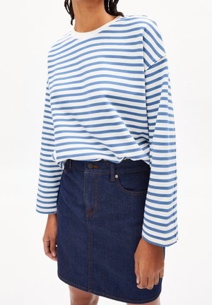 Persona que lleva una camisa de manga larga con rayas horizontales blancas y azul claro metida en una falda vaquera azul oscura.