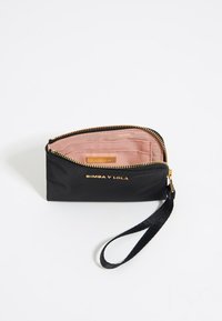 Portafoglio in nylon nero con accessori dorati, chiusura a zip e cinturino da polso. Interno in tessuto rosa con scomparti per carte e etichetta di marca.